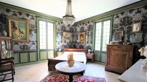 A room with a bed, a wooden cabinet, a table with a vase, and a chandelier. - Mansion and fishing pond near Bergerac (Ginestet)