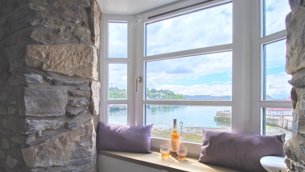 Un muro de piedra y una ventana con vistas a un lago y edificios.