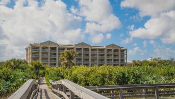 A hotel with a central courtyard, surrounded by lush greenery and a wooden boardwalk leading to the entrance.