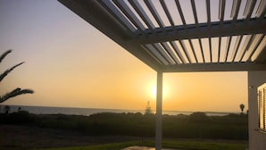 Un espacio al aire libre cubierto con vista al atardecer sobre el agua.