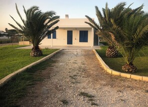 A modern building with a gravel driveway leading to a blue door.