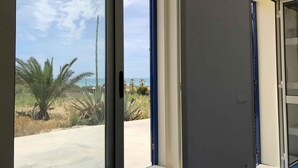 Una habitación con un amplio ventanal corredera que da a vistas de un paisaje desértico con palmeras y cielo despejado.
