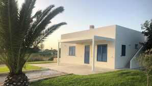Una casa moderna de un solo piso con techo plano, un porche cubierto y una pequeña escalera que lleva a la entrada.