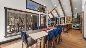 A modern kitchen with a large island, wooden beams, and a view of the outdoors. - Creekside Hideaway (Crested Butte)