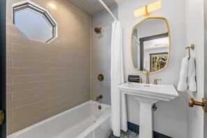 Ein Badezimmer mit Badewanne, Waschbecken, Spiegel und Duschvorhang.