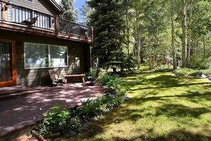 A house with a balcony, a patio with a bench, and a well-maintained lawn.