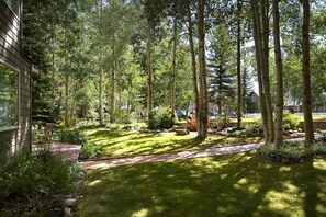 A well-maintained garden with a variety of trees, a paved pathway, and a small seating area.