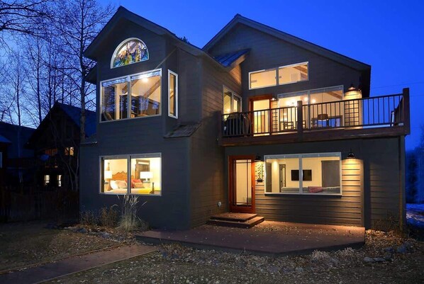 A two-story house with a balcony, large windows, and a visible staircase.