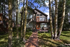 A two-story house with a visible front porch, a balcony on the upper floor, and a pathway leading to the entrance.