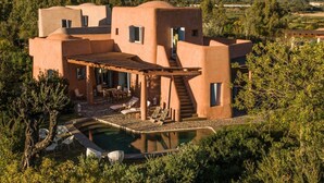 Ein modernes Haus mit Pool, Sitzgelegenheiten im Freien und einer Treppe zu den oberen Ebenen.