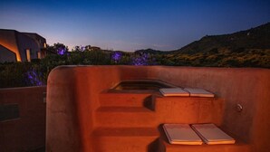Ein moderner Außenbereich mit integrierten Stufen und einem kleinen Pool, umgeben von einem angelegten Garten und einem Gebäude im Hintergrund.