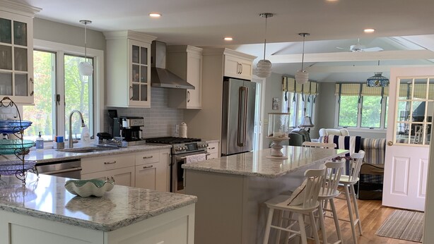 A modern kitchen with a central island, stainless steel appliances, and a dining area with a view of the outdoors. - Last Chance for August — A Bright, Breezy Stay on the Right Side of the Bridge (Harwich)