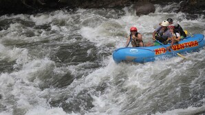 A group of people in a blue inflatable raft with 'Air Adventure' written on it, navigating through a river with white water rapids. - Río Aventura Expediciones (Jalcomulco)