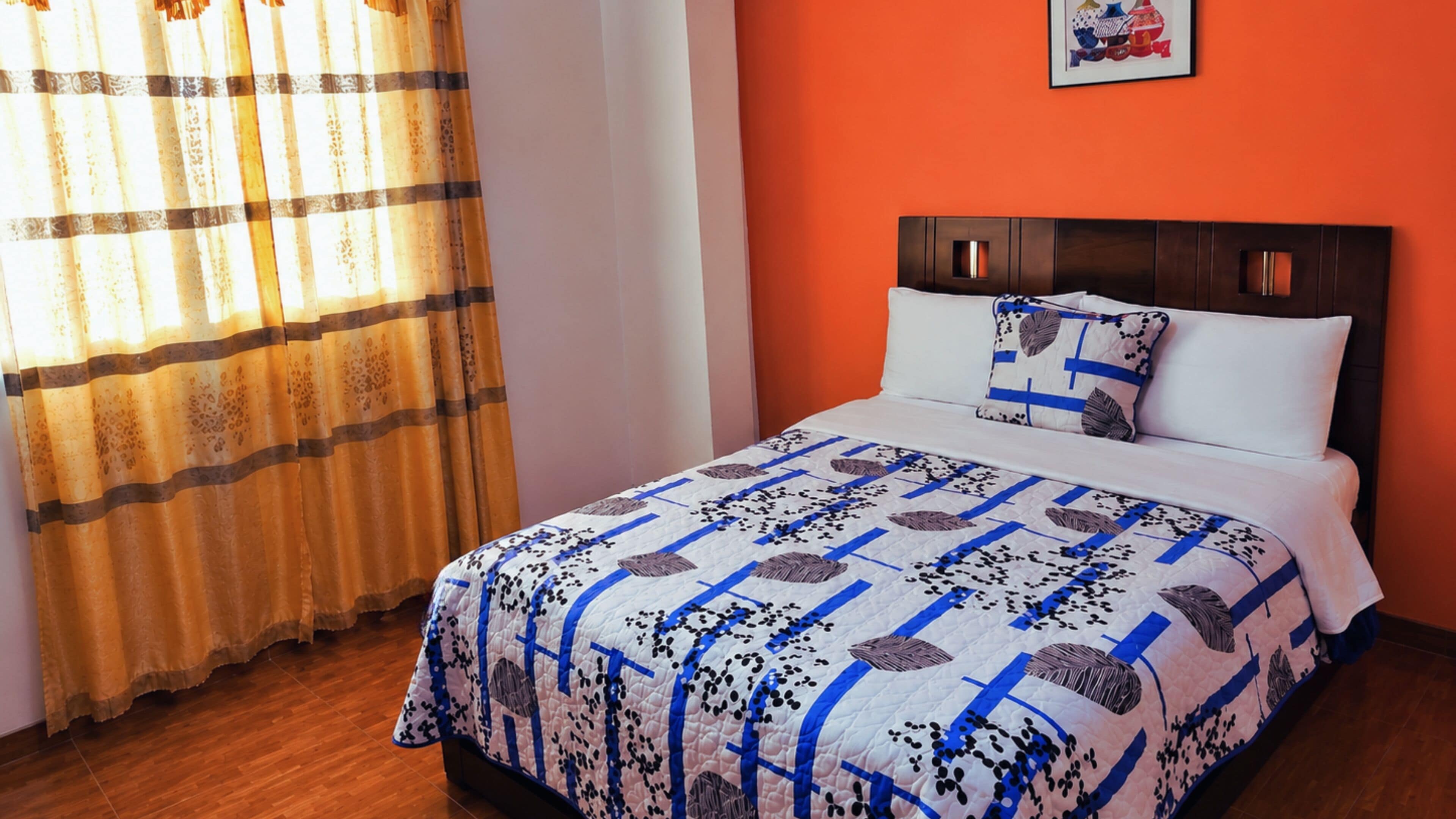 A bed with a patterned bedspread, a headboard, and a pillow with a design.
