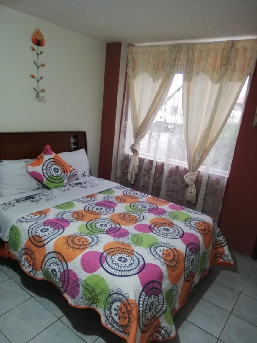 A bed with a colorful patterned bedspread, a wooden headboard, and a wall-mounted decorative item.