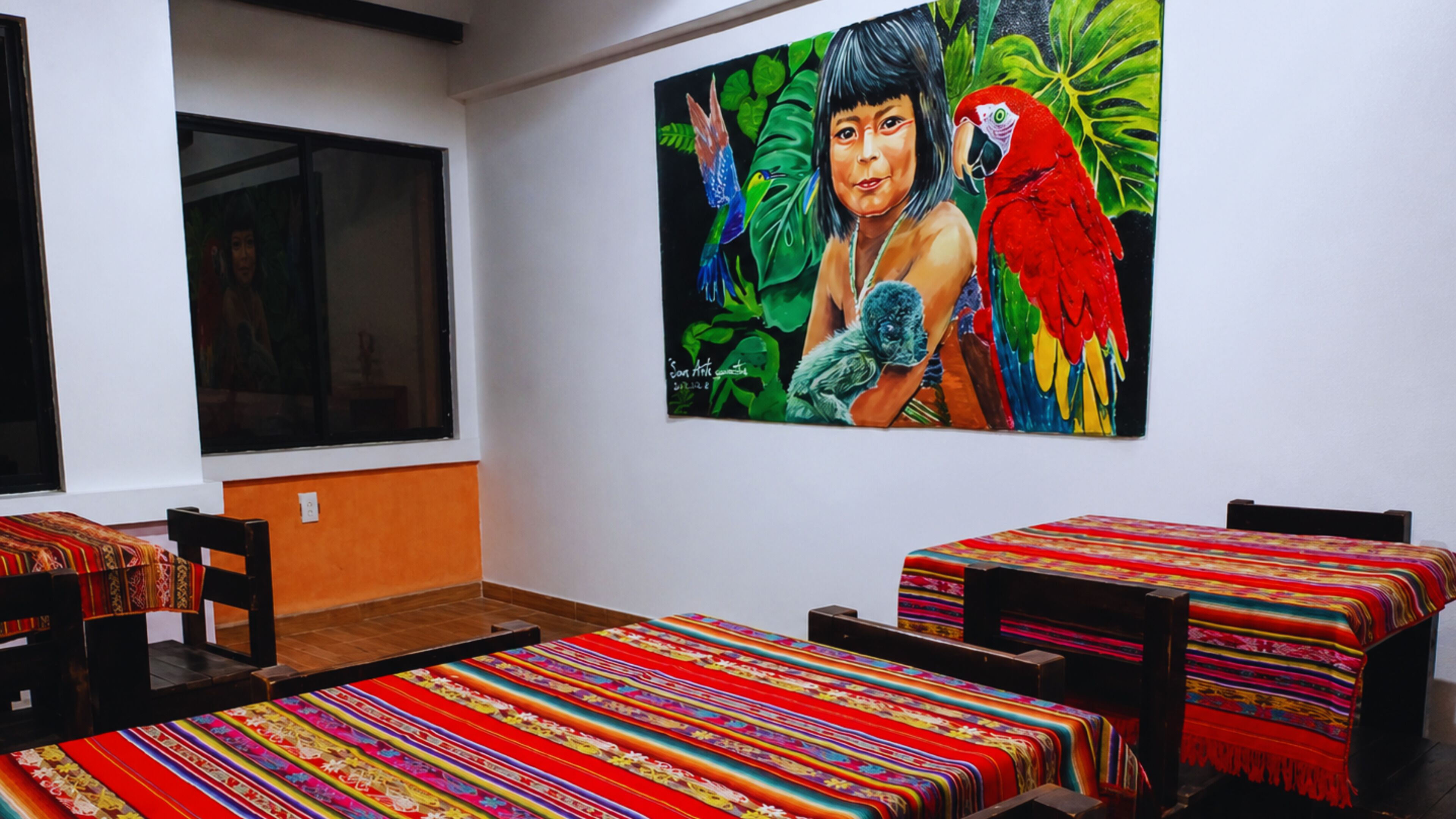 A room with two beds, a large window, and a colorful painting on the wall.