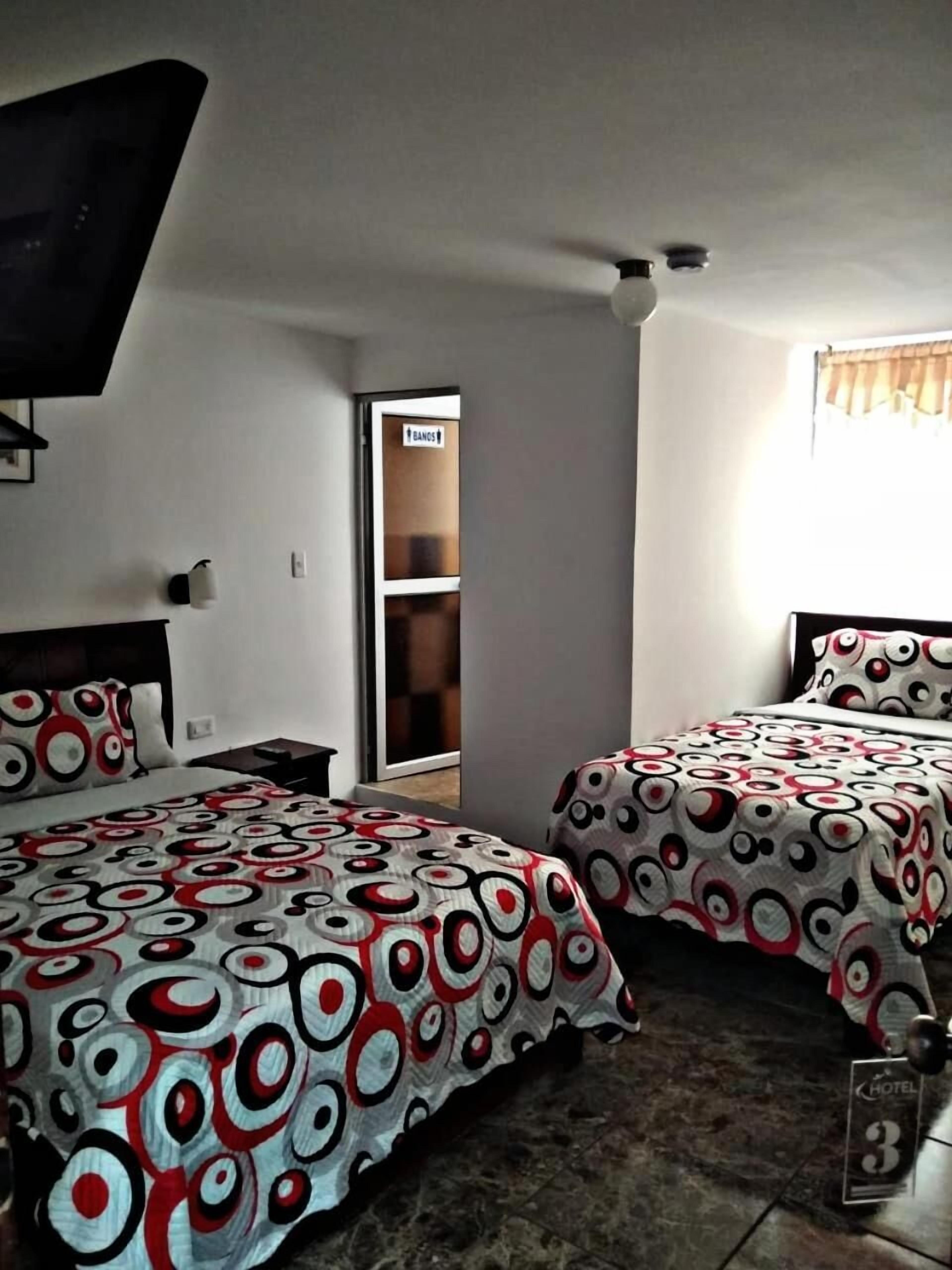 Een hotelkamer met twee bedden, een televisie, een kledingkast en een schuifdeur naar een badkamer.