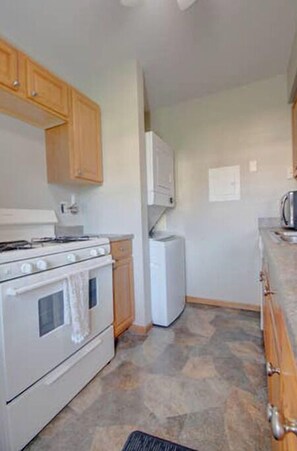 Una cocina con armarios de madera, una estufa blanca y un refrigerador.