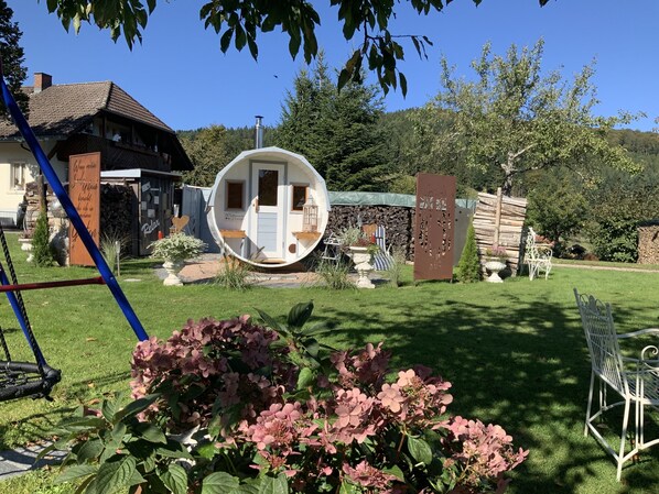 Ein Haus mit einer einzigartigen, runden Struktur im Garten, umgeben von viel Grün und blauem Himmel.