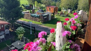 A garden with a wooden bench, a barbecue area, and a view of a forested valley. - Holiday apartment Wambach (Kleines Wiesental)