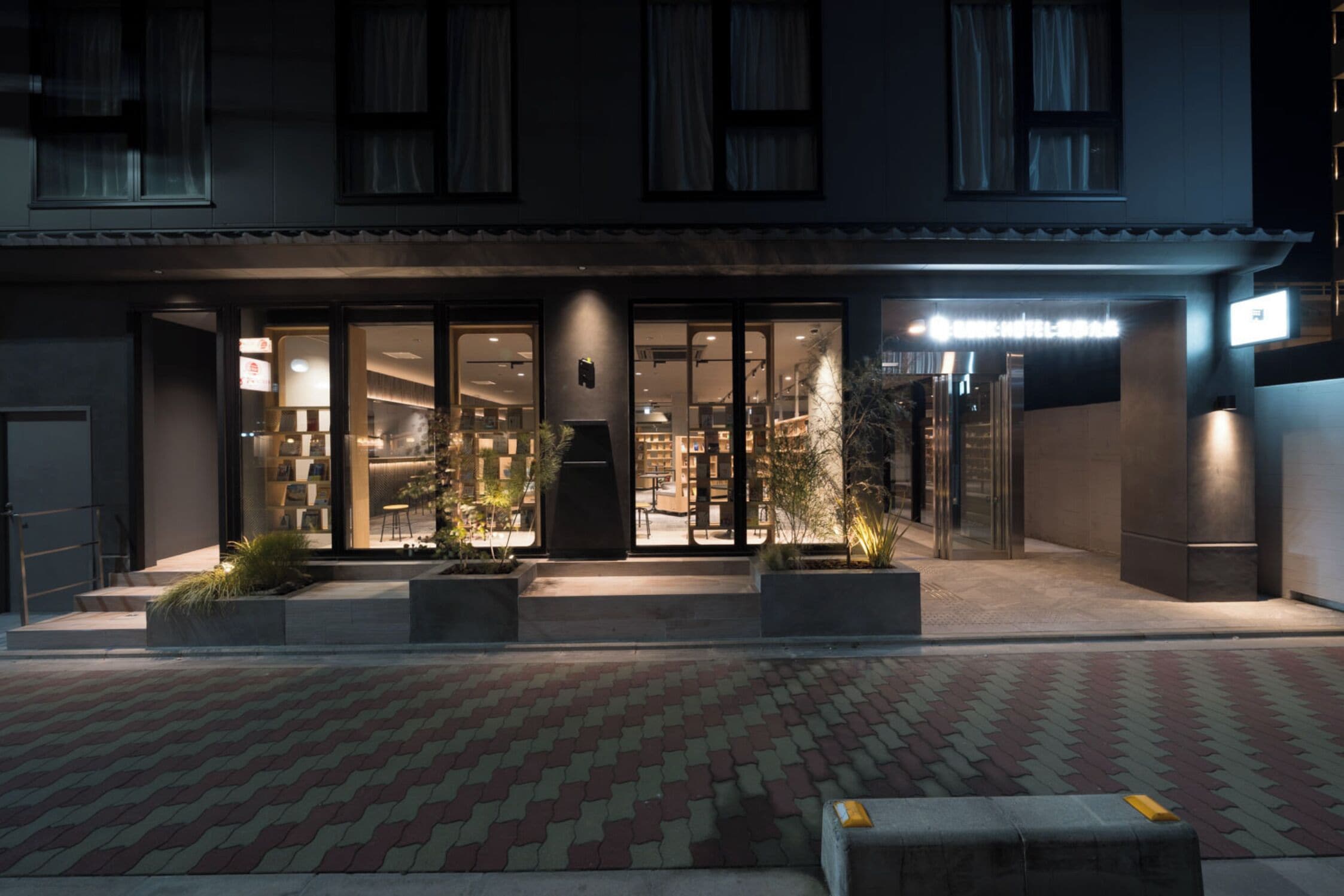 A hotel entrance with a modern design, large glass doors, and a well-lit facade.