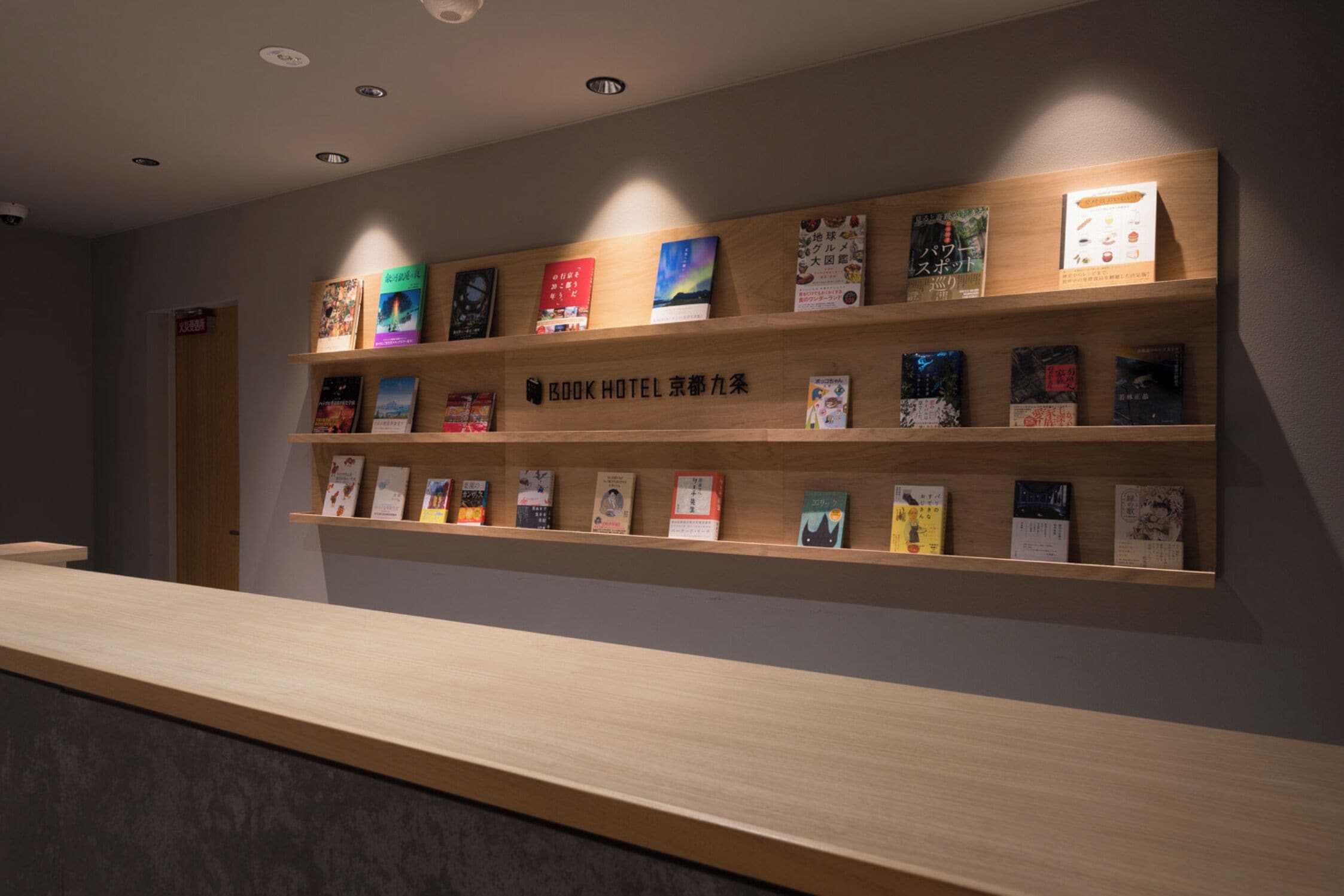 A hotel reception area with wooden shelves displaying books and a reception desk.
