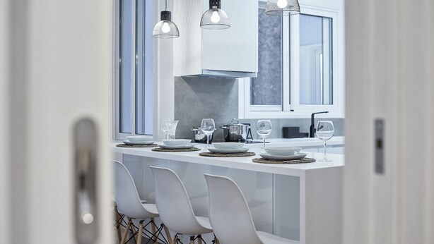 A modern kitchen with a central island, white chairs, and pendant lighting. - Kolonaki Square Executive Apartment (Athens)