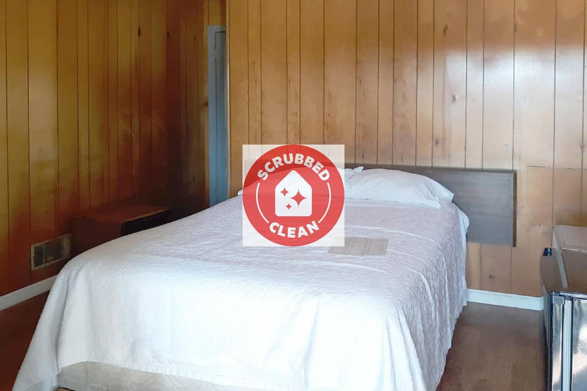 A clean, wooden-paneled room with a bed and a nightstand.