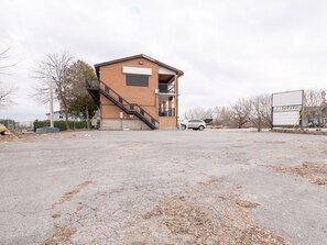 A two-story building with a staircase leading to the upper floor, a parking lot in front, and a billboard to the right. - Hotel Beaverton ON - Lake Simcoe (Brock)