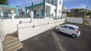 A modern two-story house with a white and teal color scheme, a car parked in the driveway, and a staircase leading to the entrance. - Abiki Mauritius (Albion)