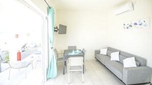 A bright, well-lit room with a dining table, chairs, a sofa, and a TV on the wall. - Abiki Mauritius (Albion)