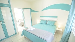 A bedroom with a bed, a bedside table, a nightstand, and a bathroom visible through an open door. - Abiki Mauritius (Albion)