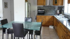 A modern kitchen with wooden cabinets, a glass dining table, and black chairs.