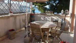 An outdoor patio with a round table and chairs, an umbrella, and potted plants.