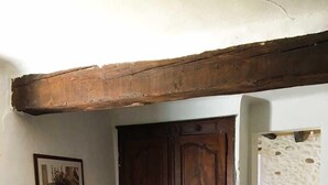 A room with a wooden door, a radiator, a framed picture on the wall, and a view of a stone wall through an open doorway. - Stay in a 16th century three story home in the Provence countryside. (Mison)