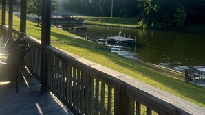 Une terrasse en bois offrant une vue sur une rivière, des bateaux et une zone herbeuse.