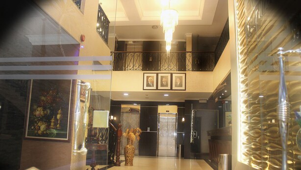 A hotel lobby with a marble floor, a chandelier, framed pictures on the wall, and an elevator. - Orient House Hotel Suites (Amman)