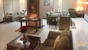A spacious living area with multiple seating options, a central table with a vase of flowers, and a fireplace. - Orient House Hotel Suites (Amman)
