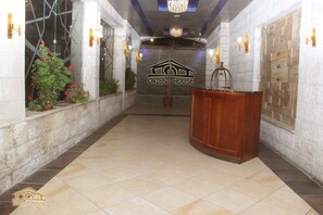 A reception area with a marble wall, a reception desk, and a chandelier. - Orient House Hotel Suites (Amman)
