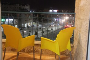 Two yellow chairs by a window overlooking a busy street at night. - Orient House Hotel Suites (Amman)