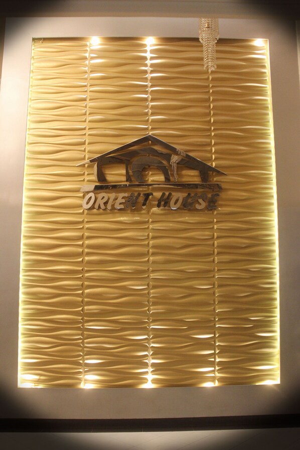 A textured wall with a window and a sign that reads "ORIENT HOUSE". - Orient House Hotel Suites (Amman)