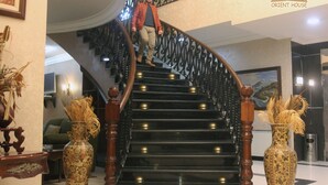 A grand staircase with ornate railings and a person ascending. - Orient House Hotel Suites (Amman)