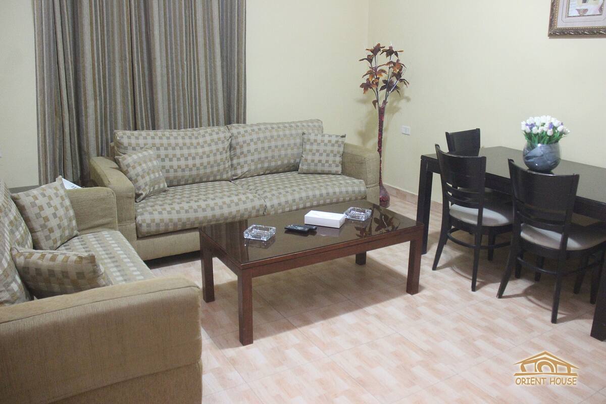 A living room with a sofa, a coffee table, and a dining table with chairs.