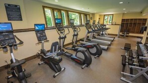 Un gimnasio con cintas de correr, elípticas y bancos de pesas.