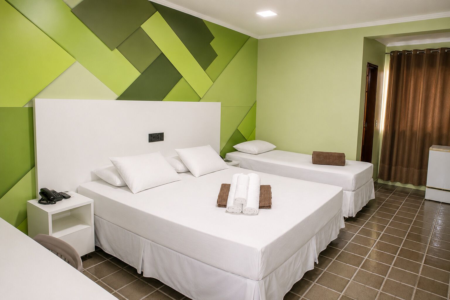 Una habitación de hotel con dos camas, una mesita de noche y un baño visible a través de una puerta abierta.