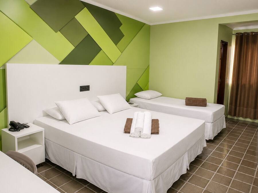 Una habitación de hotel con dos camas, una mesita de noche y un baño visible a través de una puerta abierta.