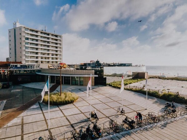 A hotel with a modern design, featuring a large building with multiple floors and a parking area with bicycles.