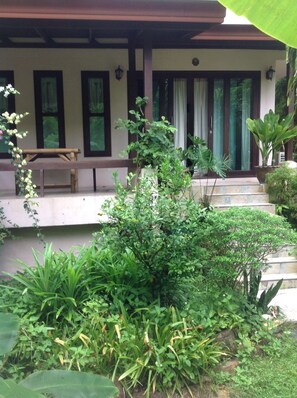 Relax in a serene outdoor space surrounded by lush greenery and a covered seating area.