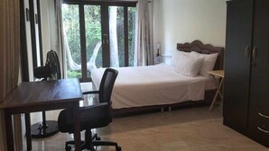A bedroom with a bed, a desk, a chair, and a wardrobe.
