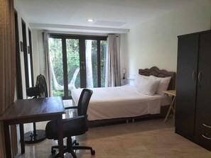 Enjoy a peaceful retreat with a large bed, desk, and wardrobe, plus a window offering a view of lush surroundings.